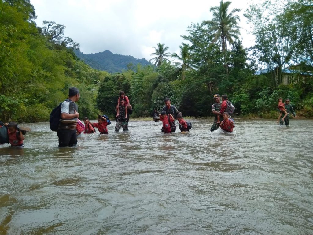 Anggota TNI membantu siswa menyeberang sungai untuk pergi ke sekolah, Kamis (10/1)Foto Istimewa
