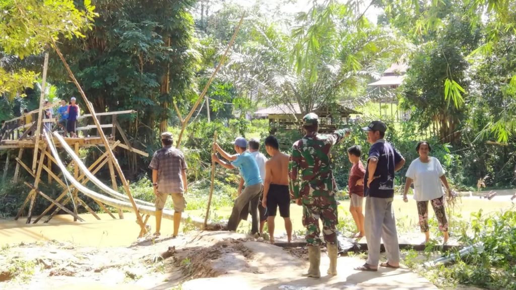 Warga dan TNI berjibaku membangun kembali jembatan bambu yang terputus akibat banjir bandang di Dusun Lintang Pelaman, Rabu (9/1)