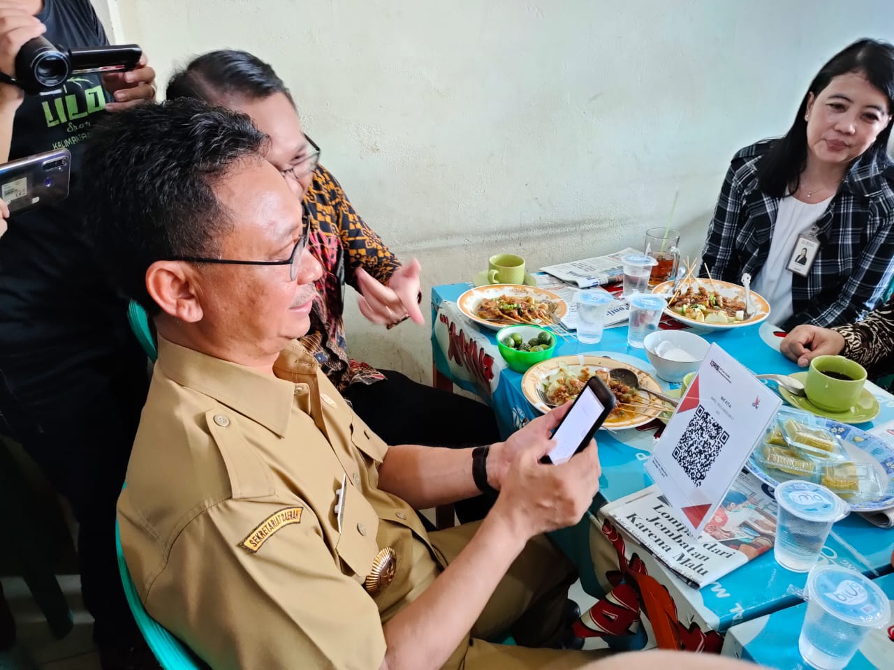 Wali Kota Pontianak, Edi Rusdi Kamtono menggunakan sebuah aplikasi uang elektronik  melalui QRIS di sebuah warung kopi di Pasar Flamboyan.